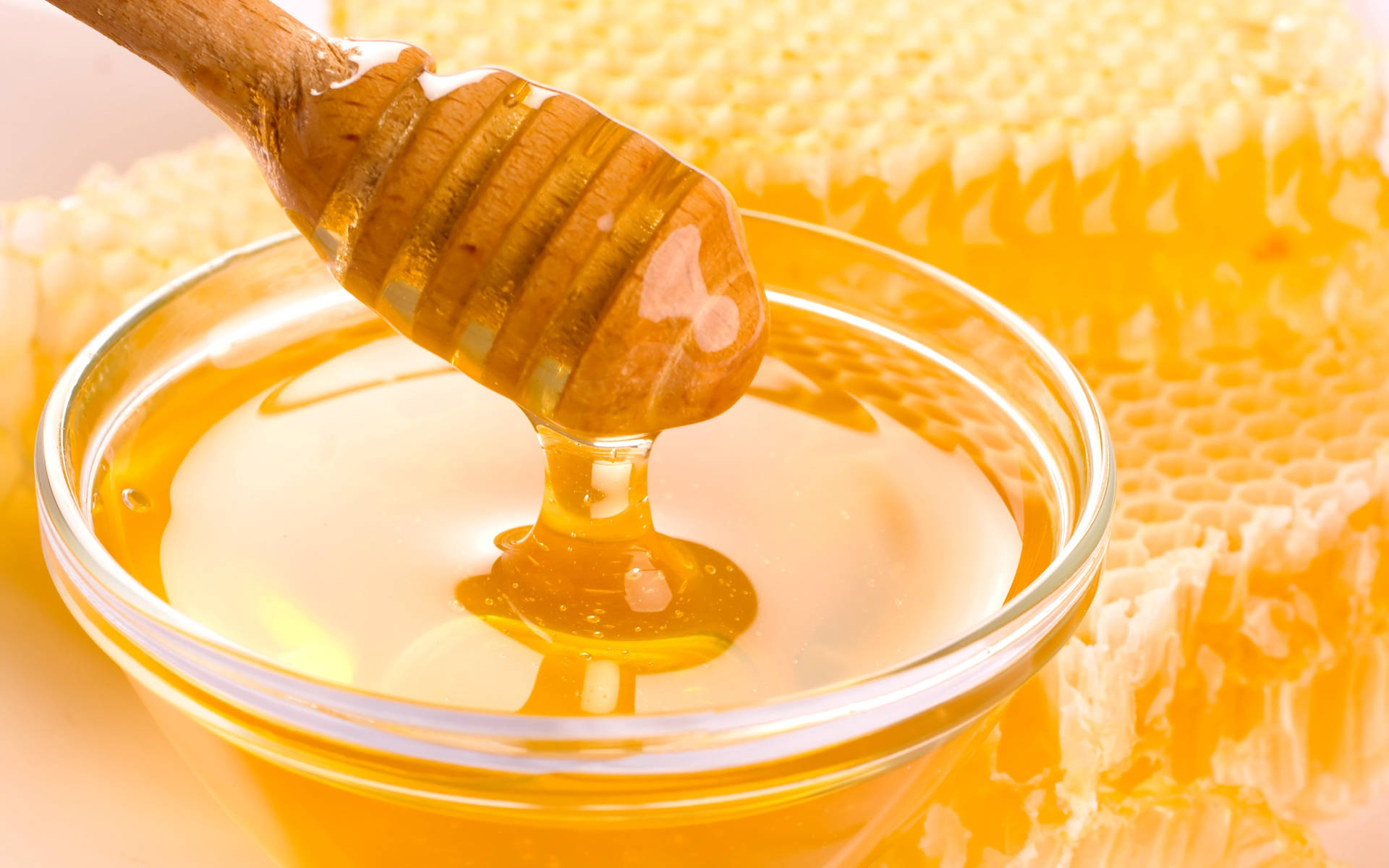 Glass Bowl Of Honey With Honeycomb Background