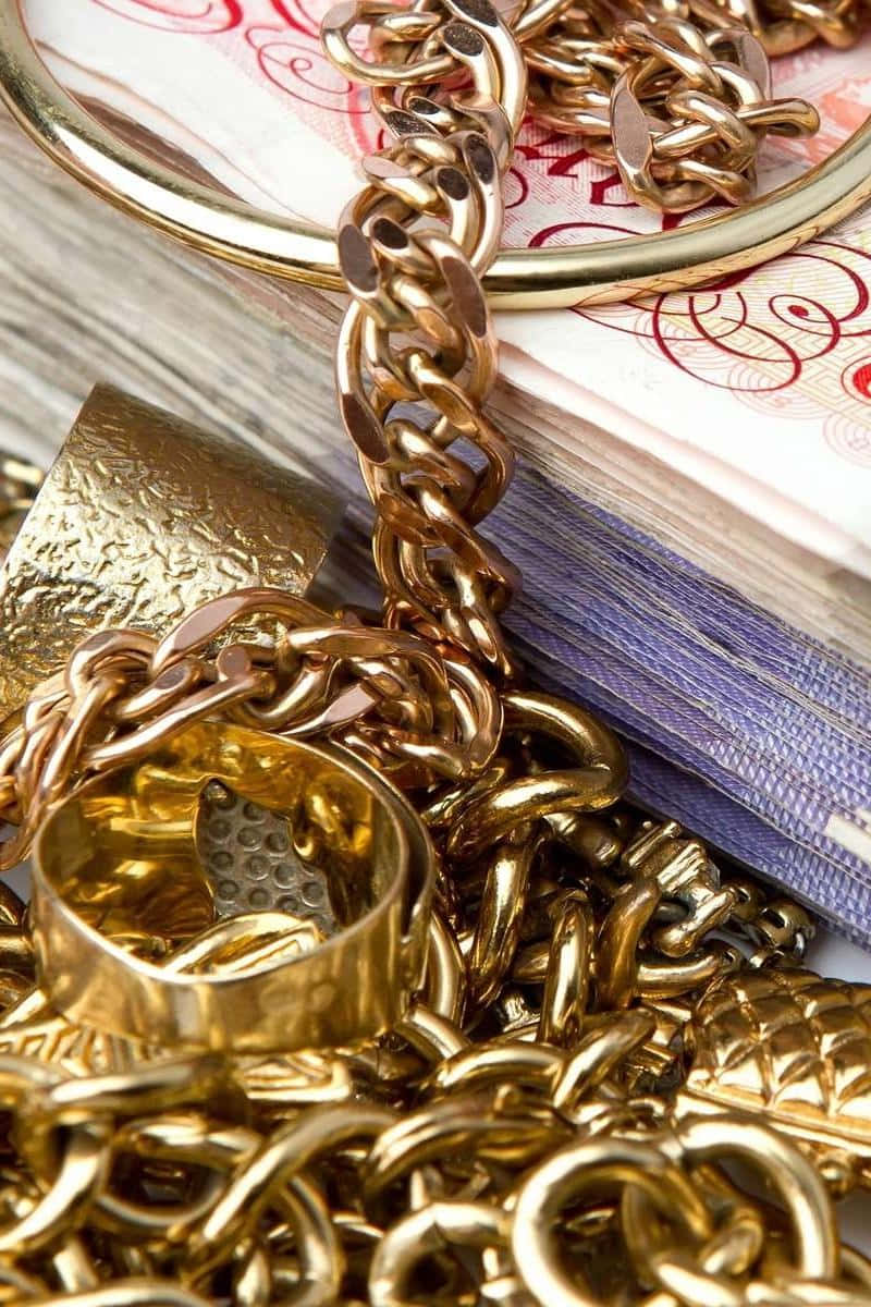 Gold Chains And Rings On A Pile Of Money Background