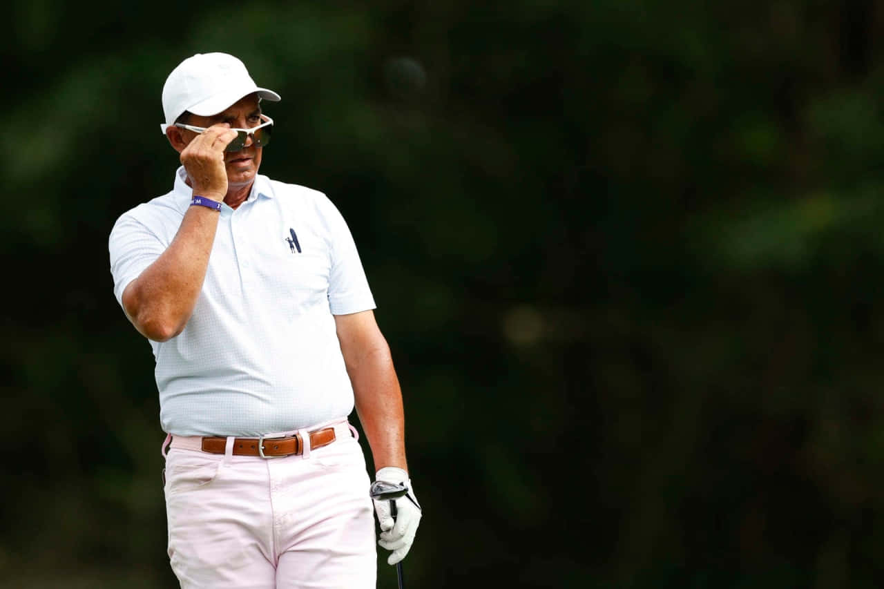 Golfer Adjusting Sunglasseson Course Background