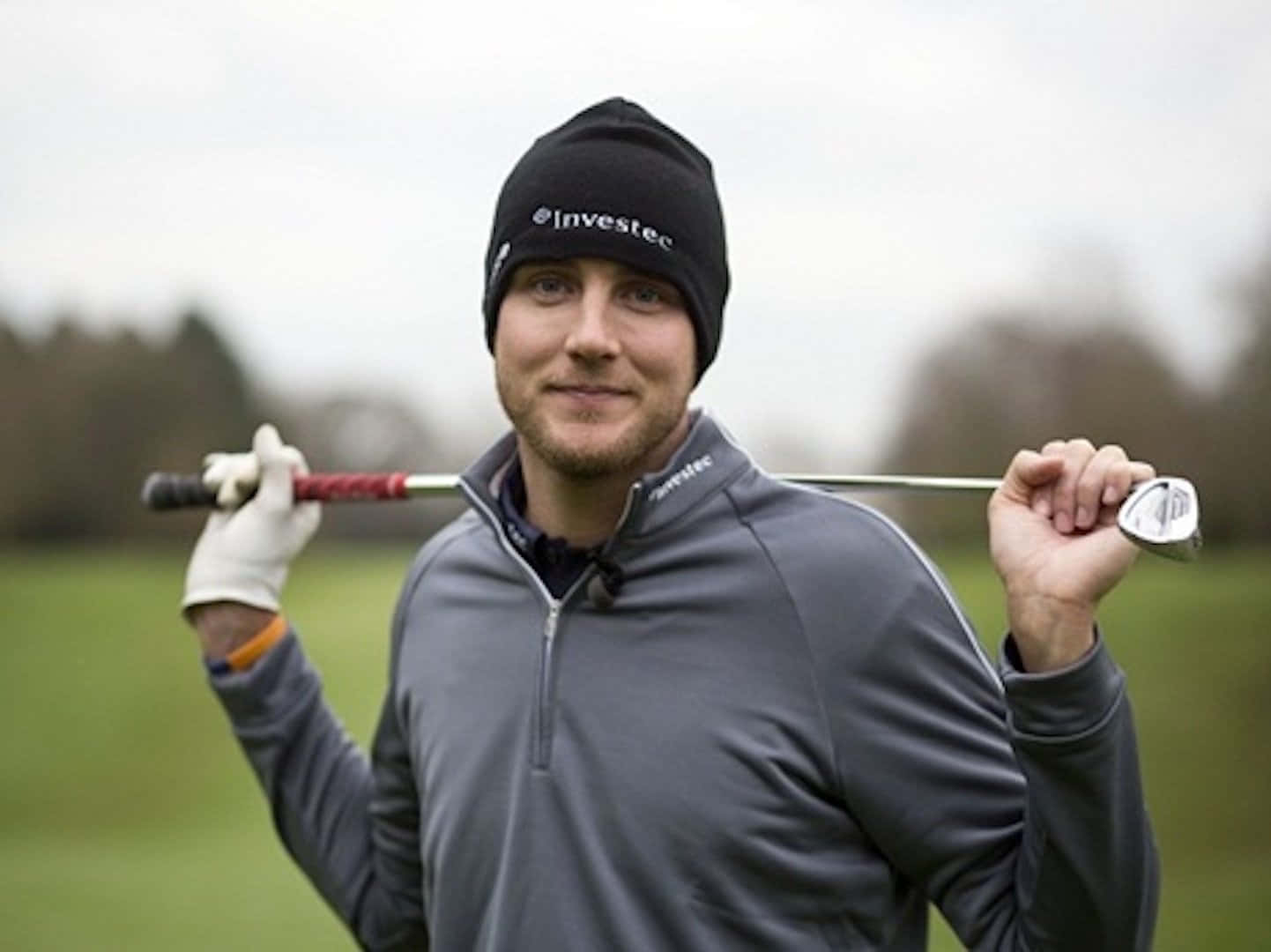 Golfer Smiling With Club Outdoors Background