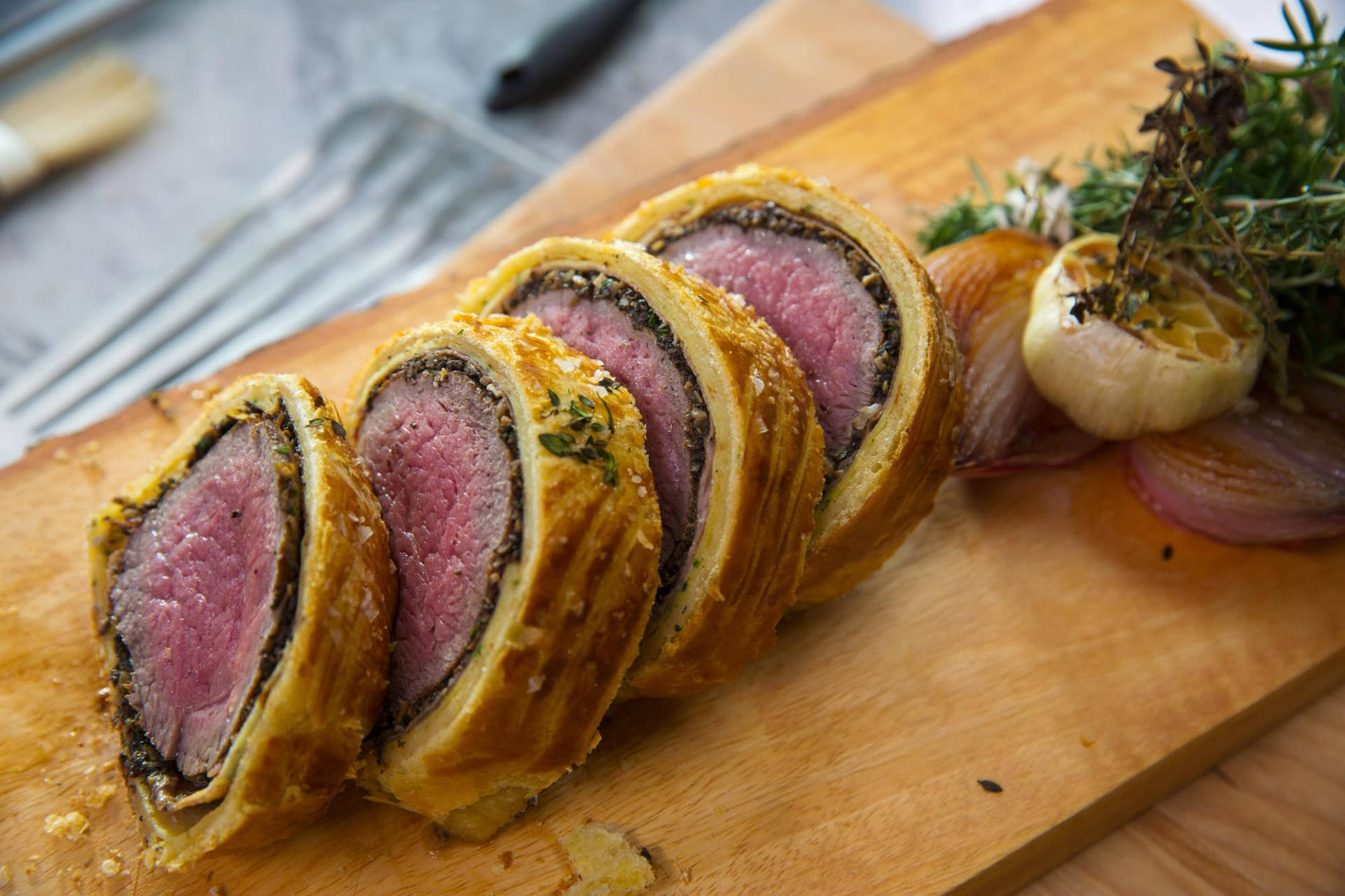 Gourmet Beef Wellington Garnished With Garlic And Rosemary Background