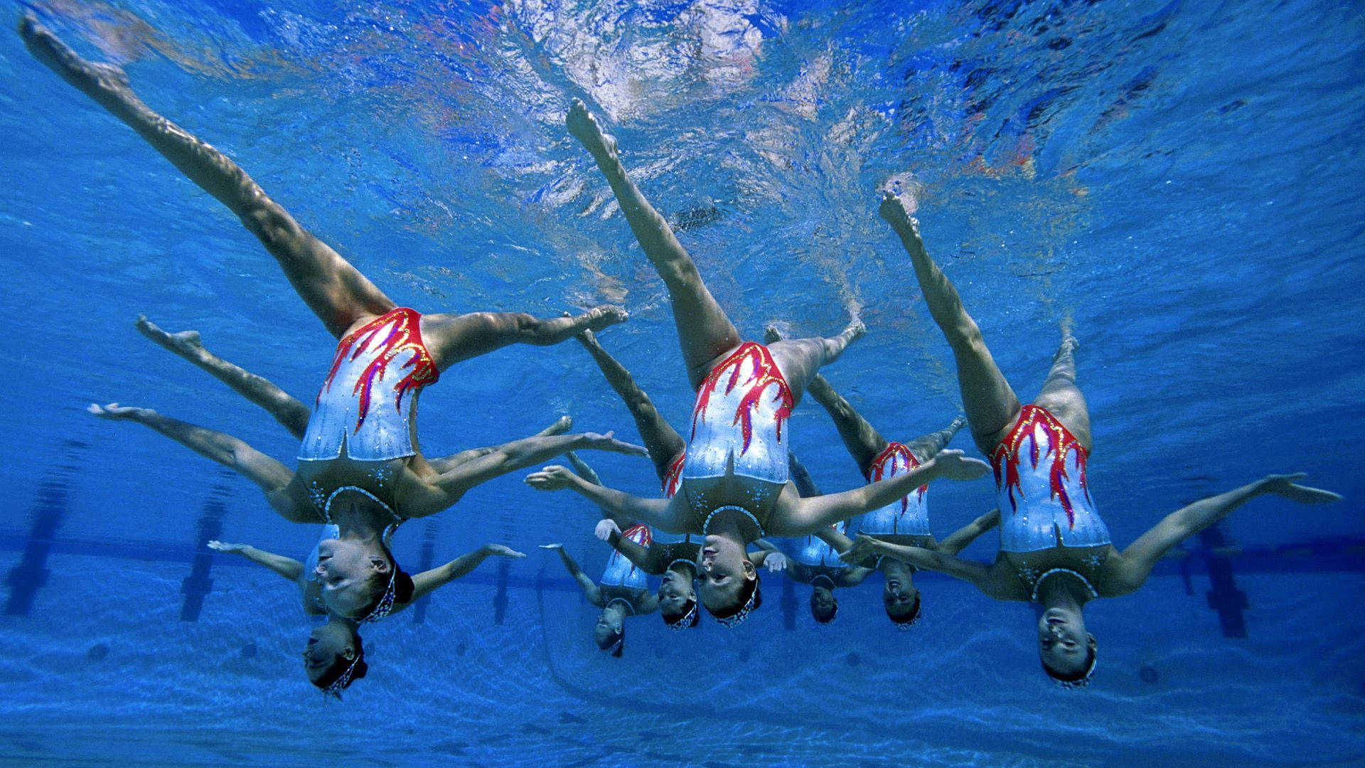 Graceful Underwater Ballet: Synchronized Swimming Upside Down Background