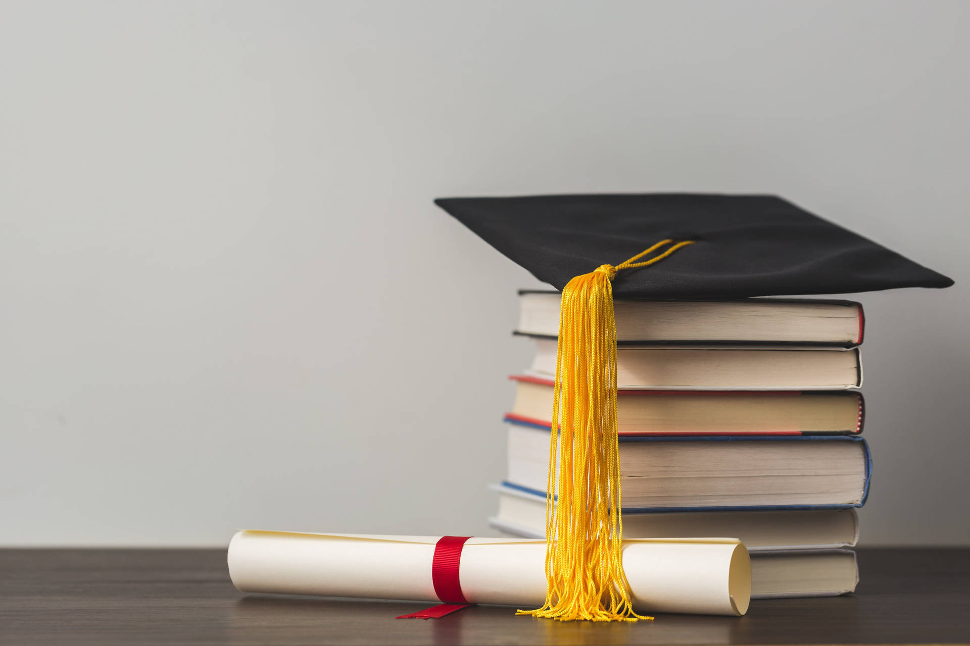 Graduate Cap On Top Of Reference Books Near A Diploma Background