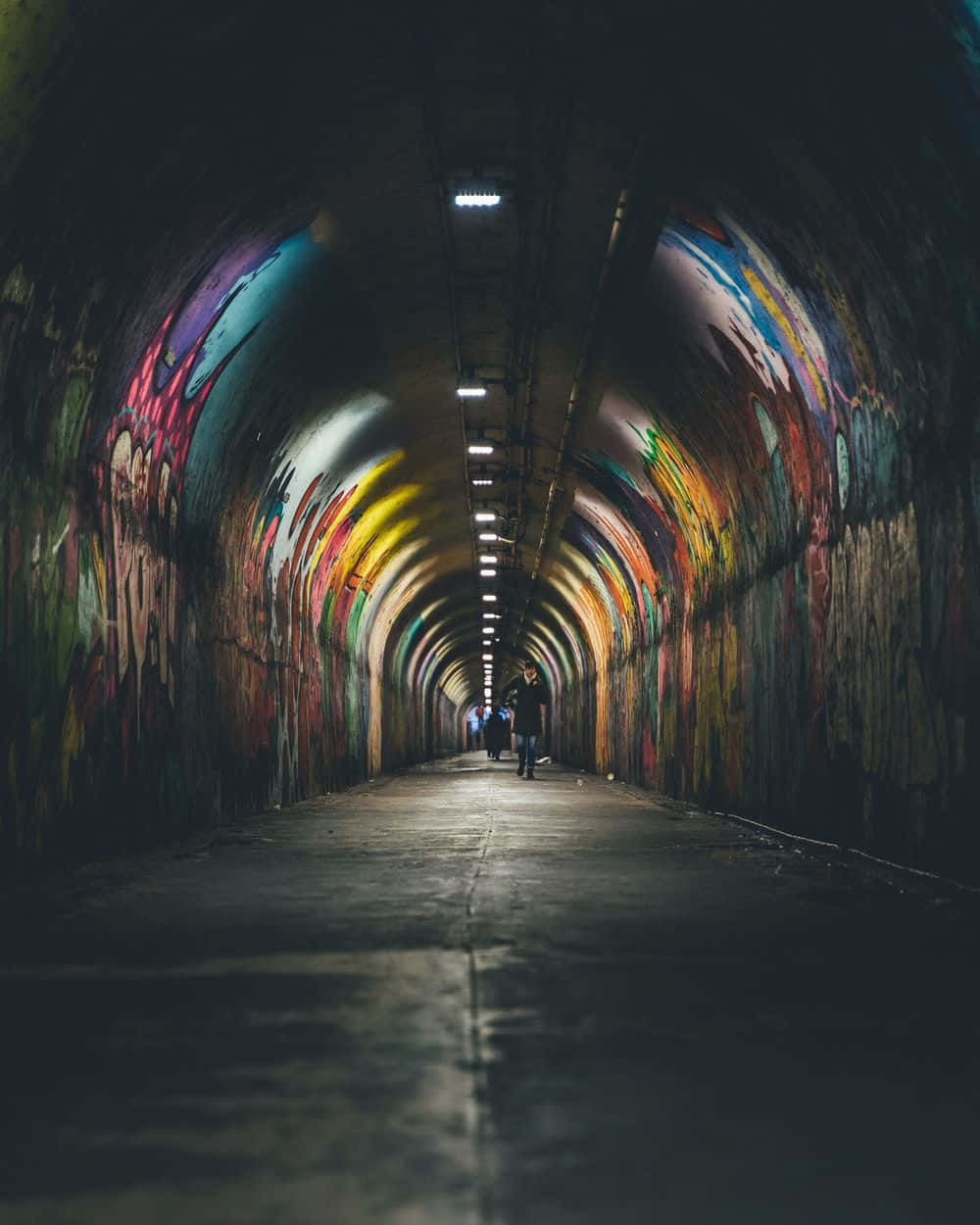 Graffiti Adorned Tunnel With Pedestrians Background