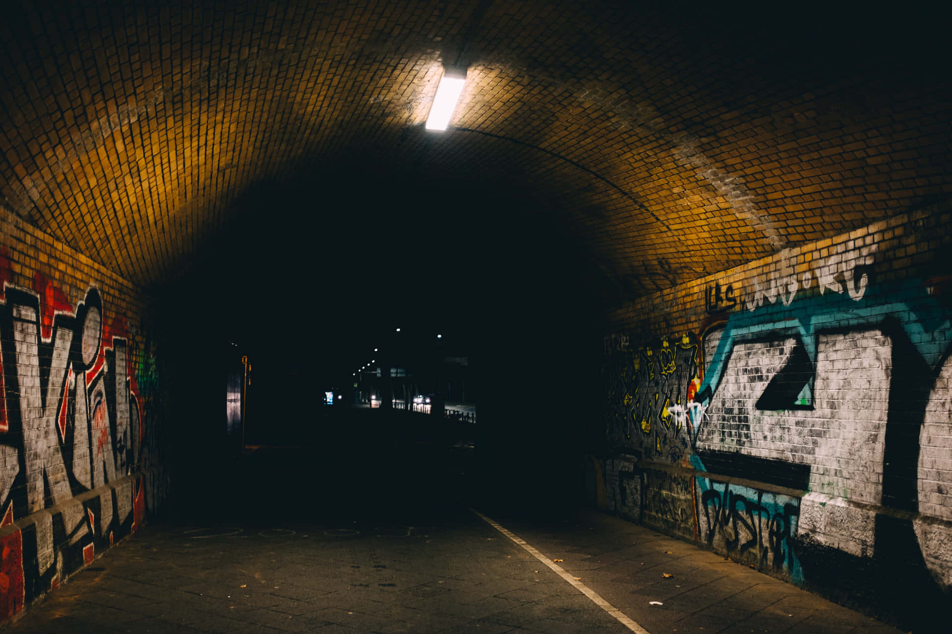 Graffiti Adorned Urban Tunnel At Night Background