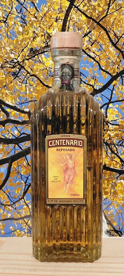 Gran Centenario Tequila Reposado Against A Tree Background