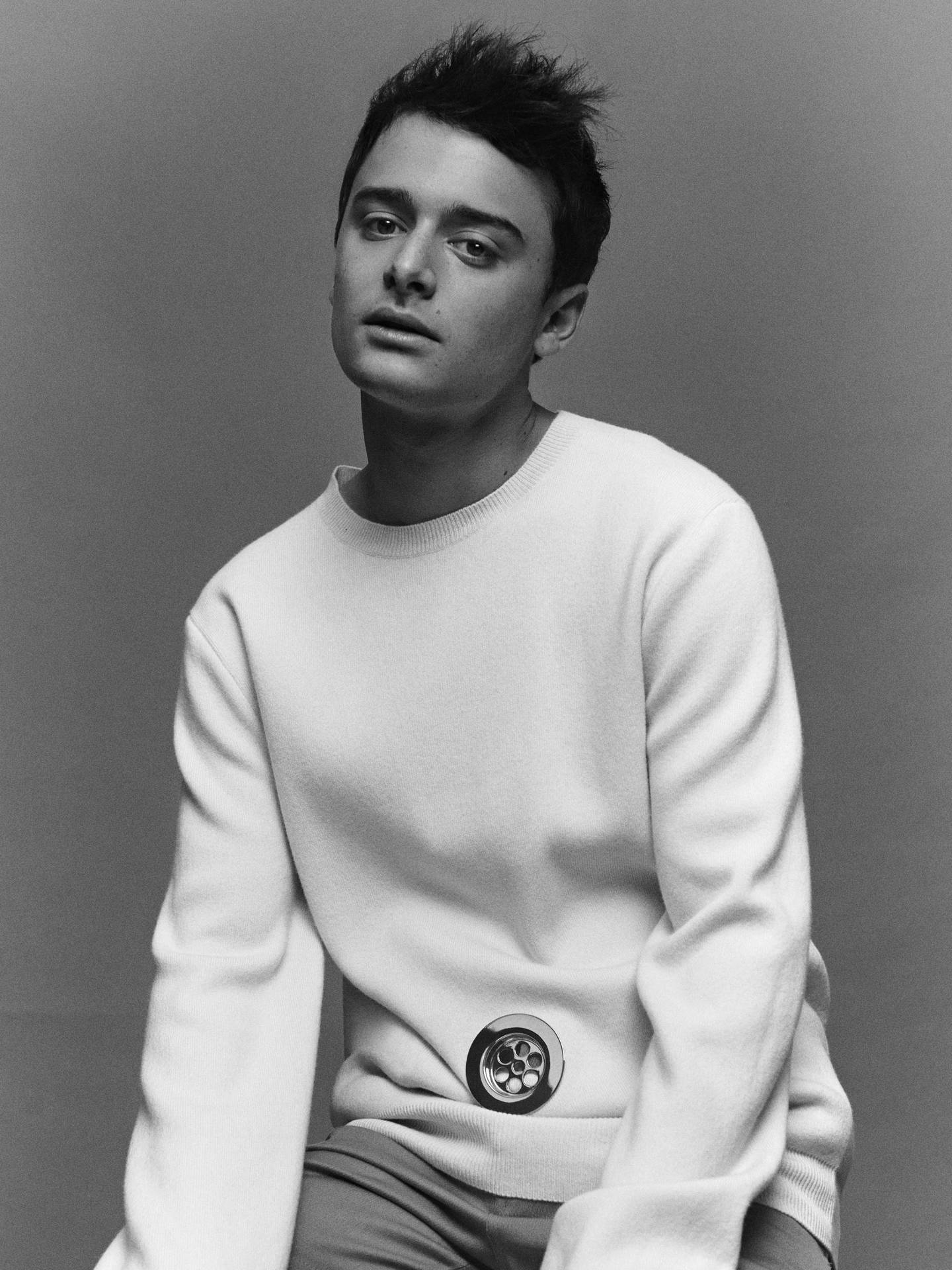 Grayscale Noah Schnapp In White Sweater Background