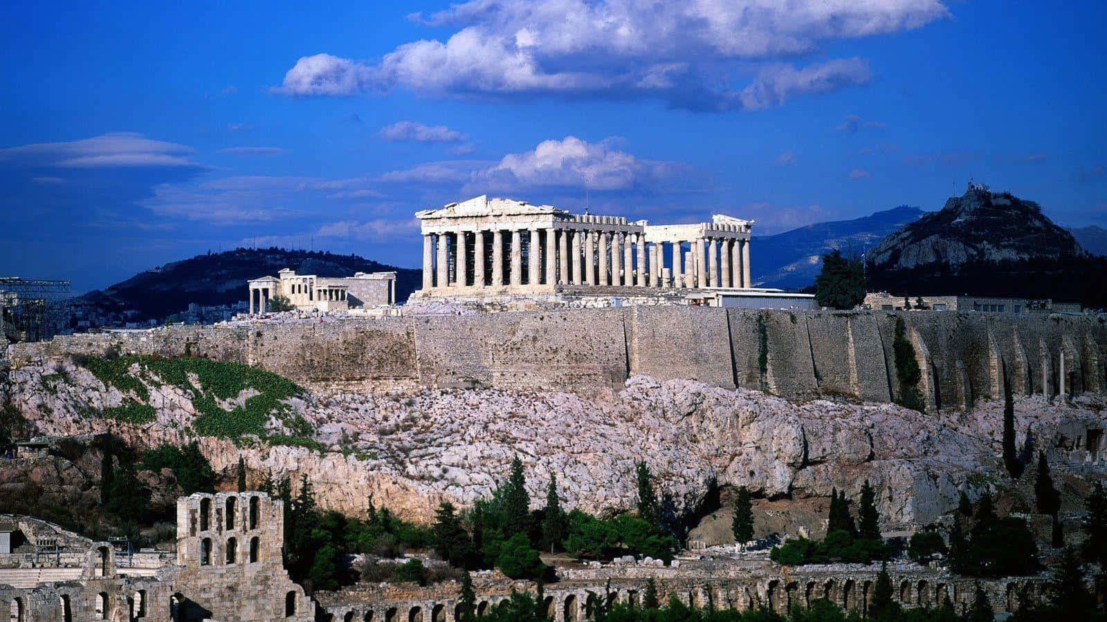 Greek Acropolis Atop A Rocky Elevation Background