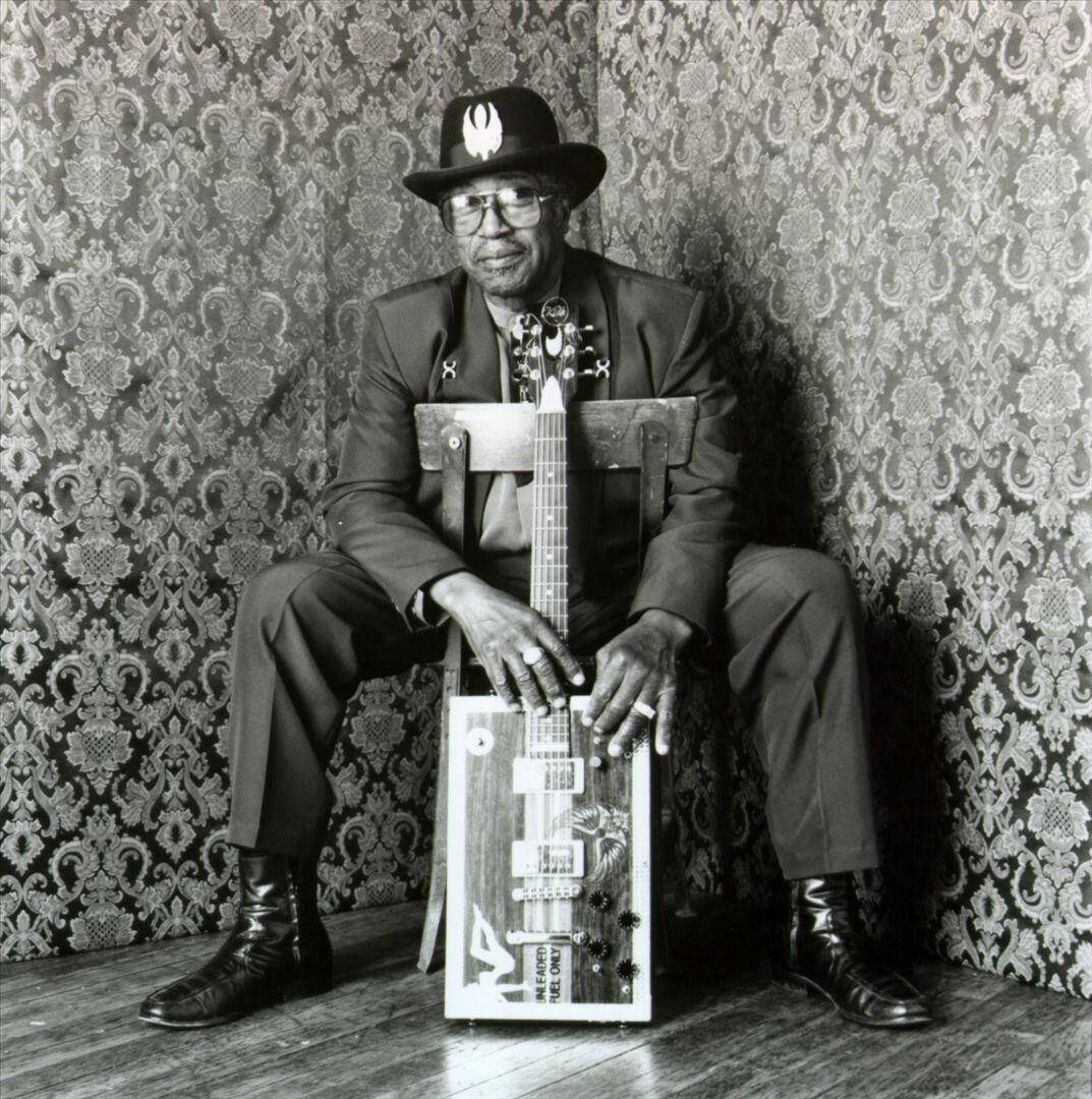 Greyscale Bo Diddley Sitting On Chair Background