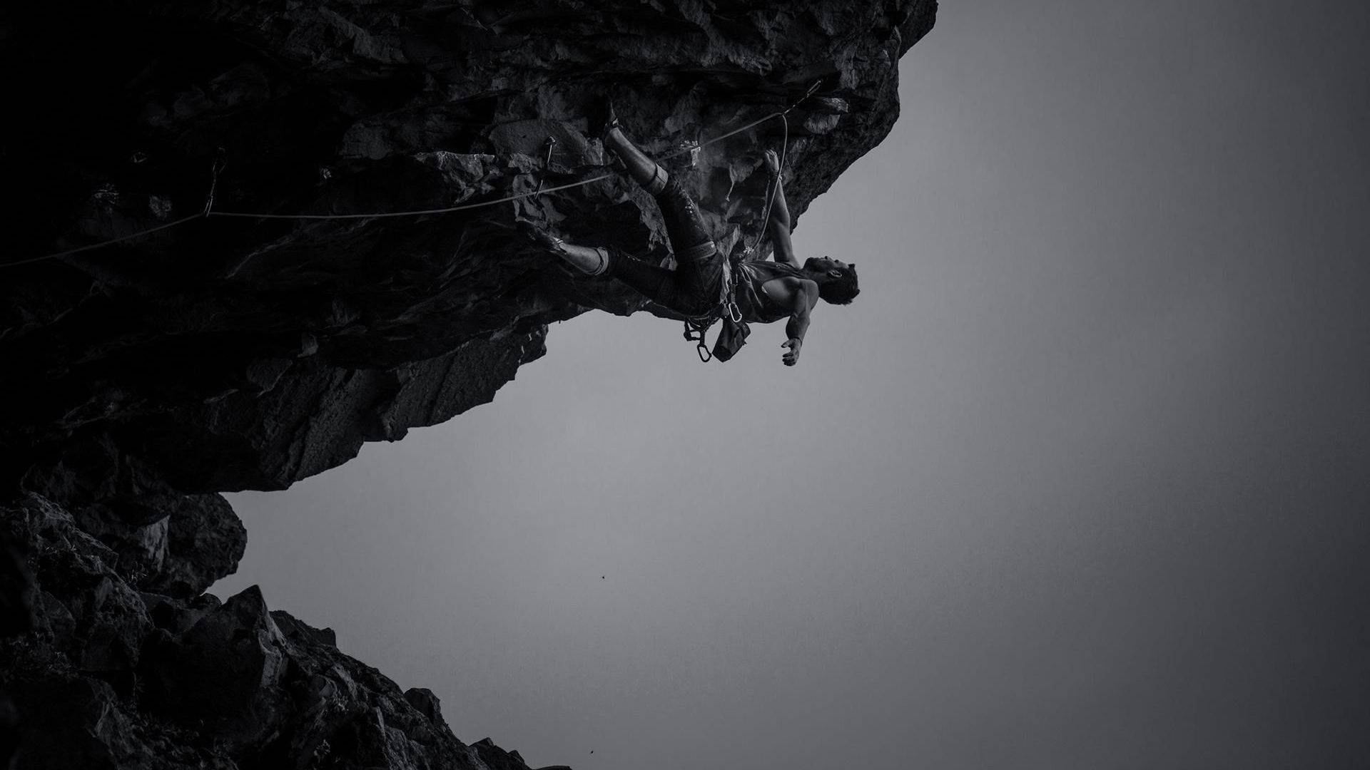 Greyscale Photo Of Man Rock Climbing Background