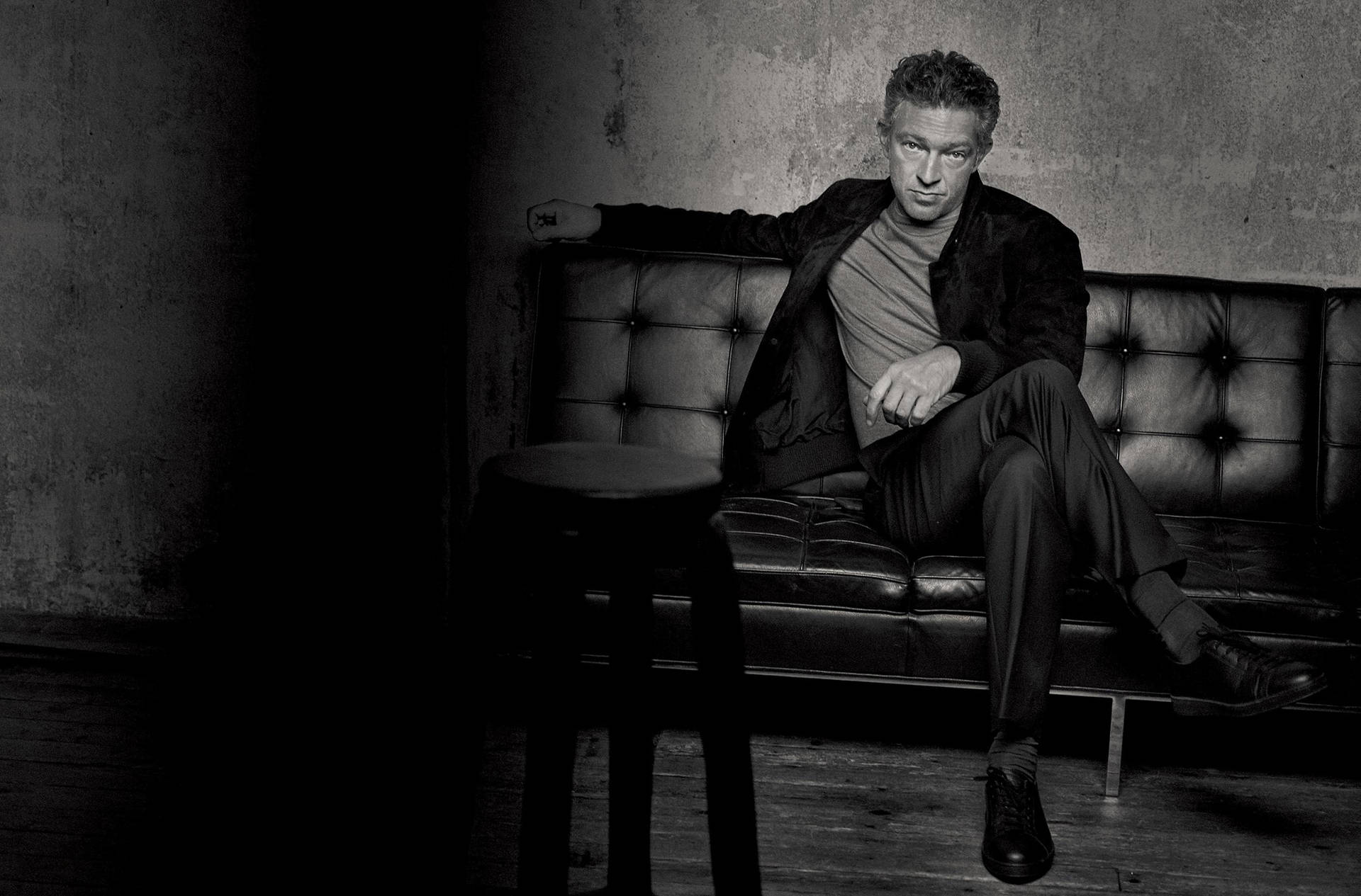 Greyscale Vincent Cassel Sitting On Couch Background