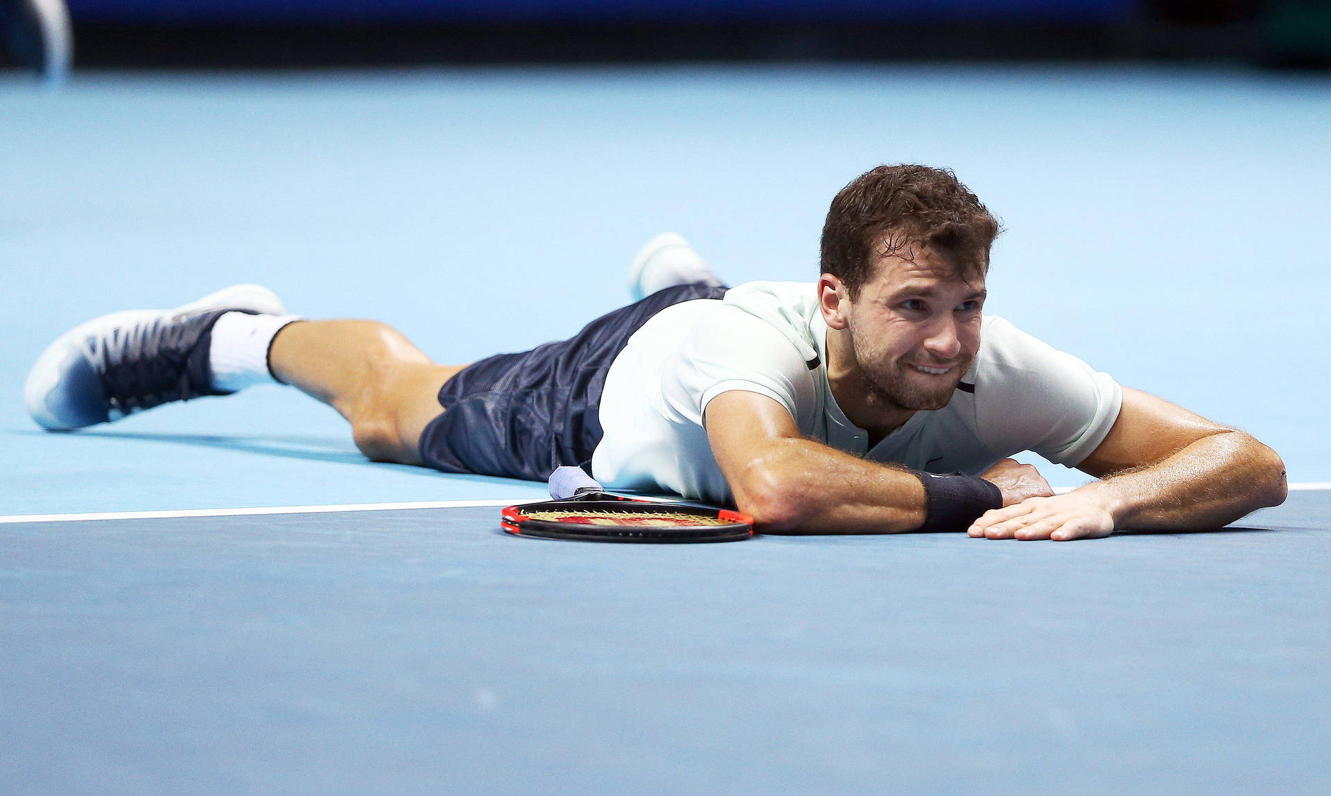 Grigor Dimitrov Laying On Tennis Court Background