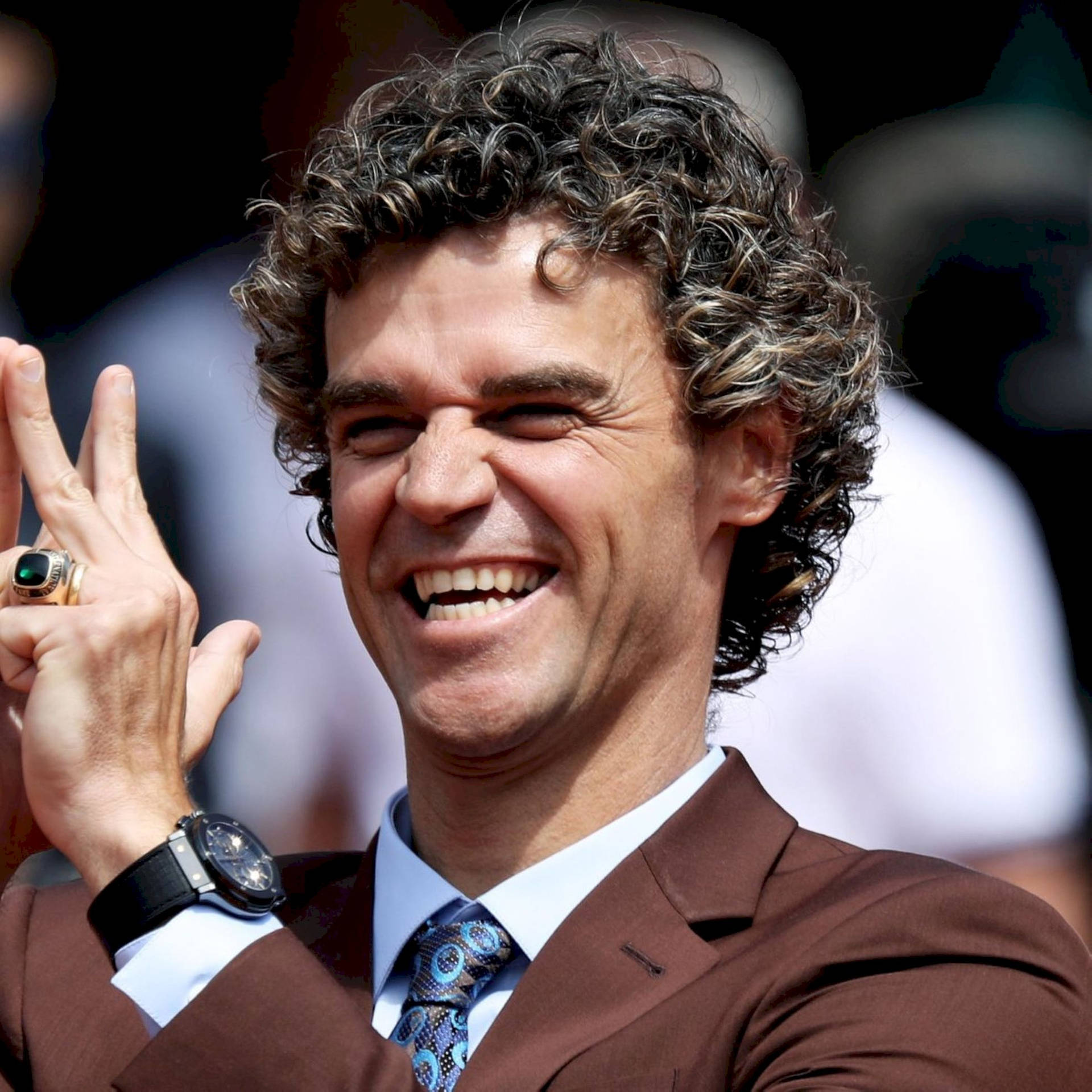 Gustavo Kuerten Smiling In Brown Suit Background