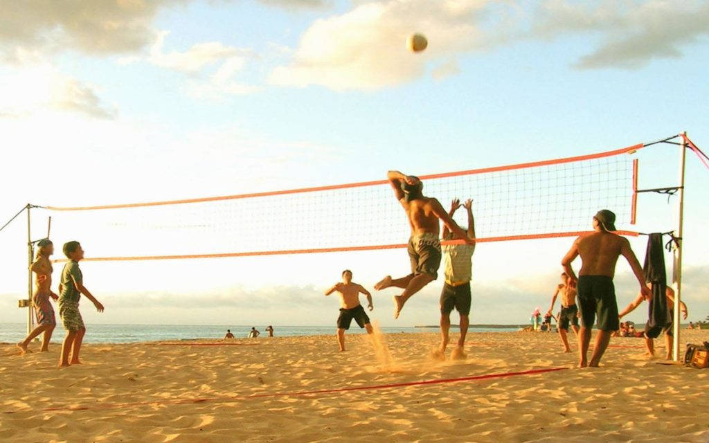 Guys Playing Beach Volleyball On A Sunny Day Background