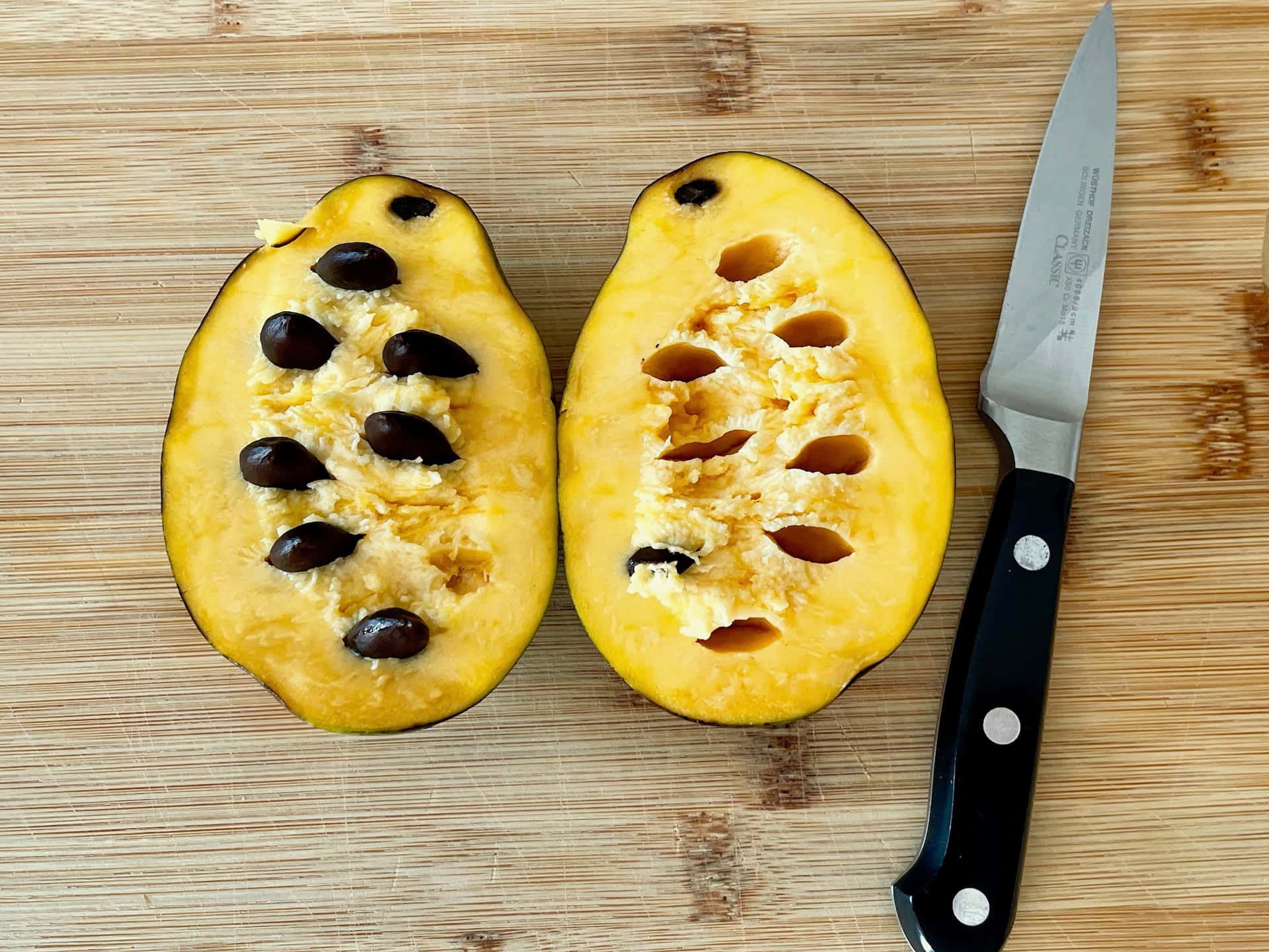 Halved Pawpaw With Seeds And Knife