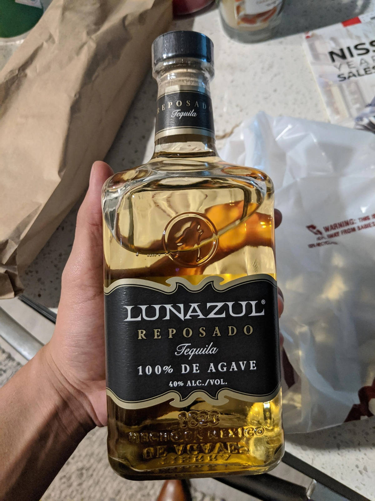 Hand Holding Lunazul Reposad Tequila Background