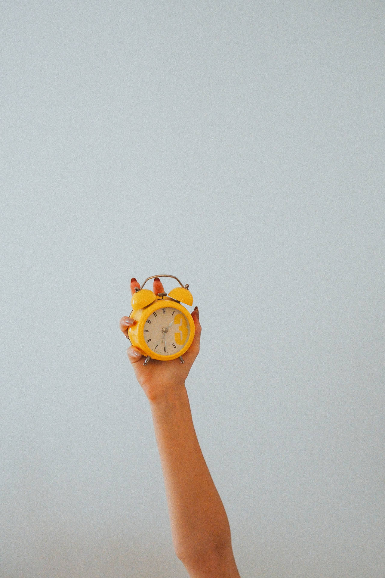 Hand Holding Yellow Alarm Clock Background