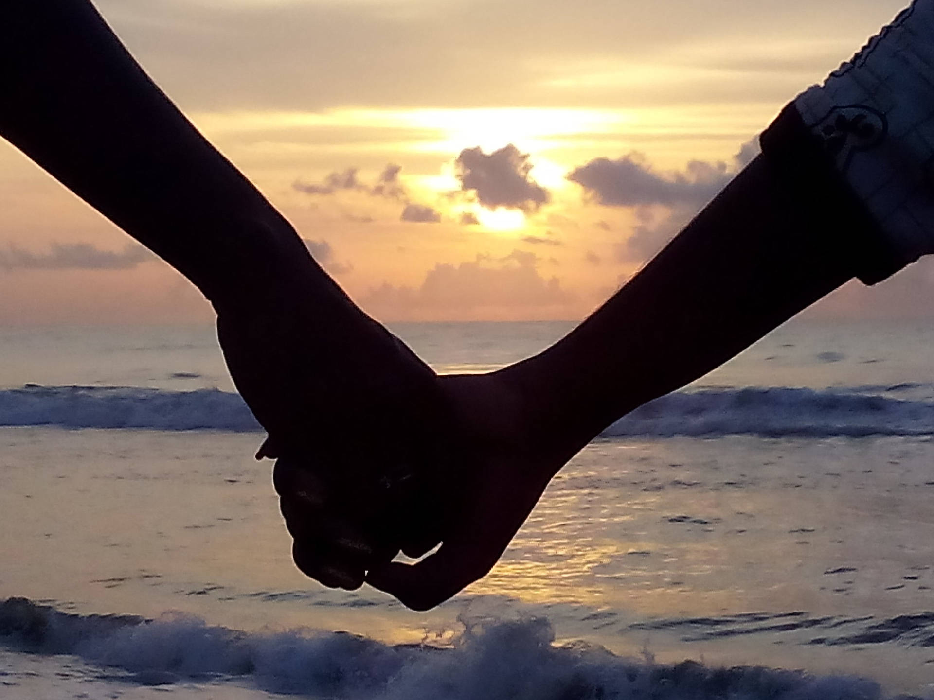 Hand In Hand Facing Ocean Background