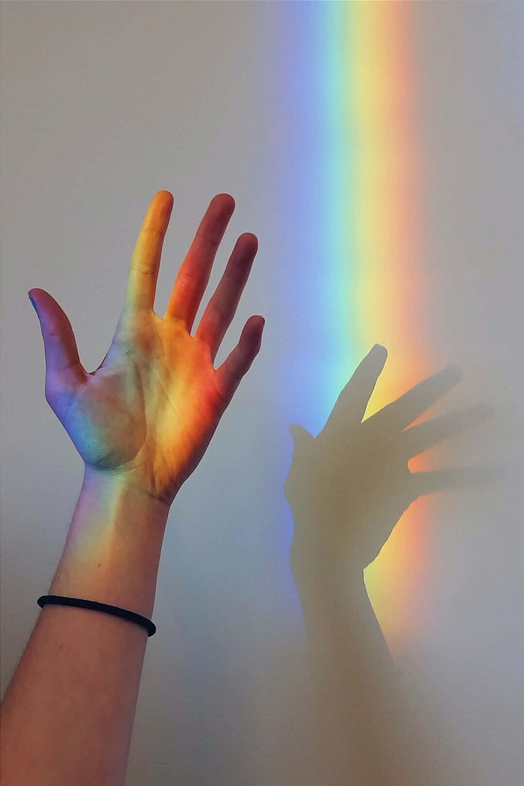 Hand Playing With The Aesthetic Rainbow Mobile Background