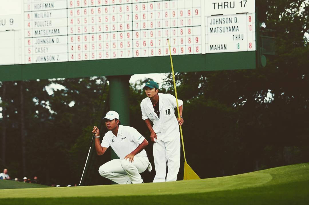 Hideki Matsuyama And Caddie Looking At Hole Background