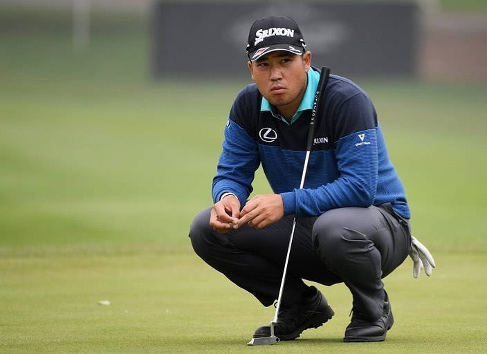 Hideki Matsuyama Squatting On Golf Course Background