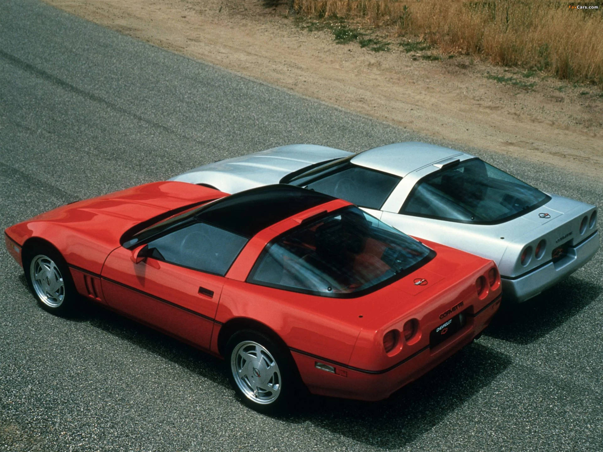 High-speed Elegance: Two C4 Corvettes Racing On Open Roads Background
