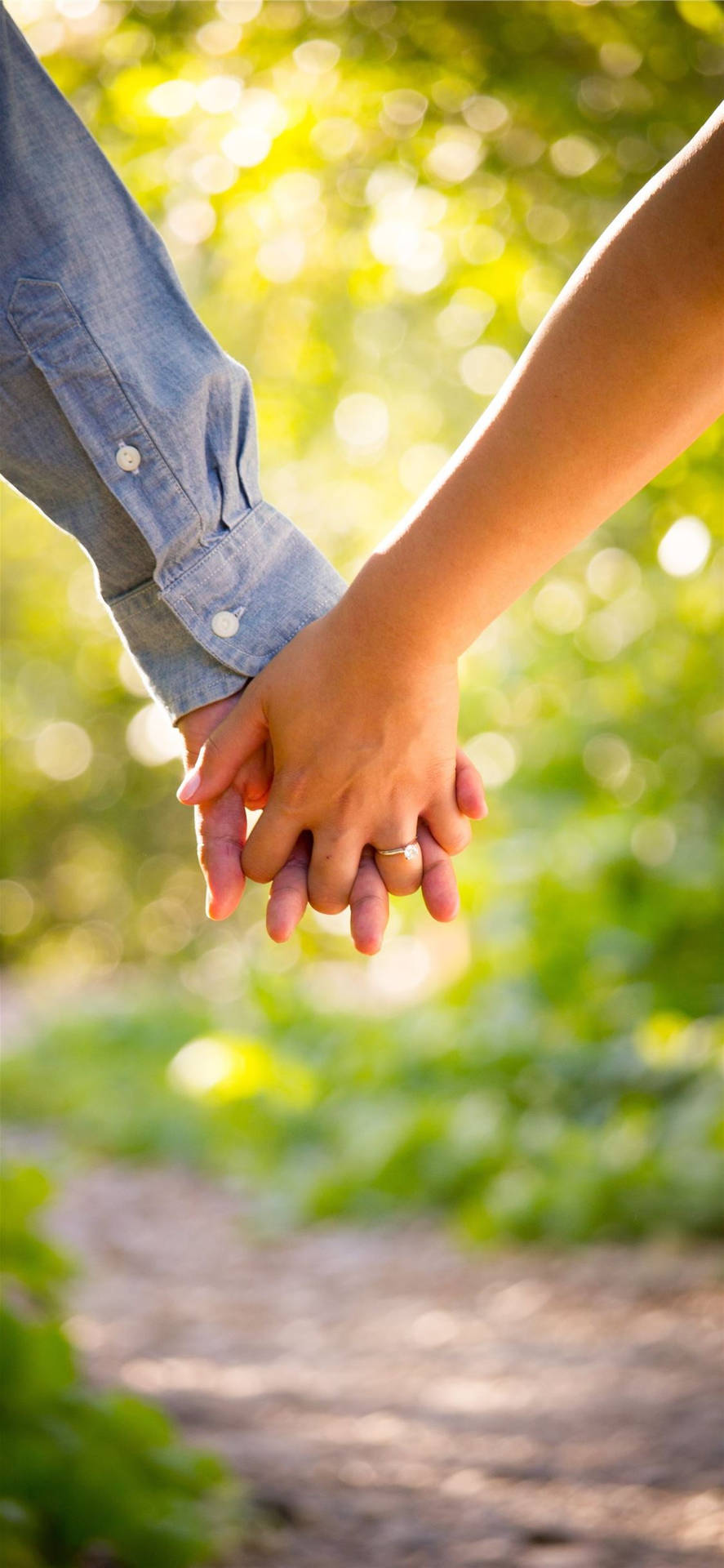 Holding Hands In Green Grass And Leaves Background