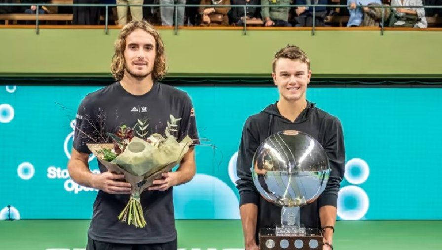 Holger Rune Battling Against Stefanos Tsitsipas In A Tennis Match Background