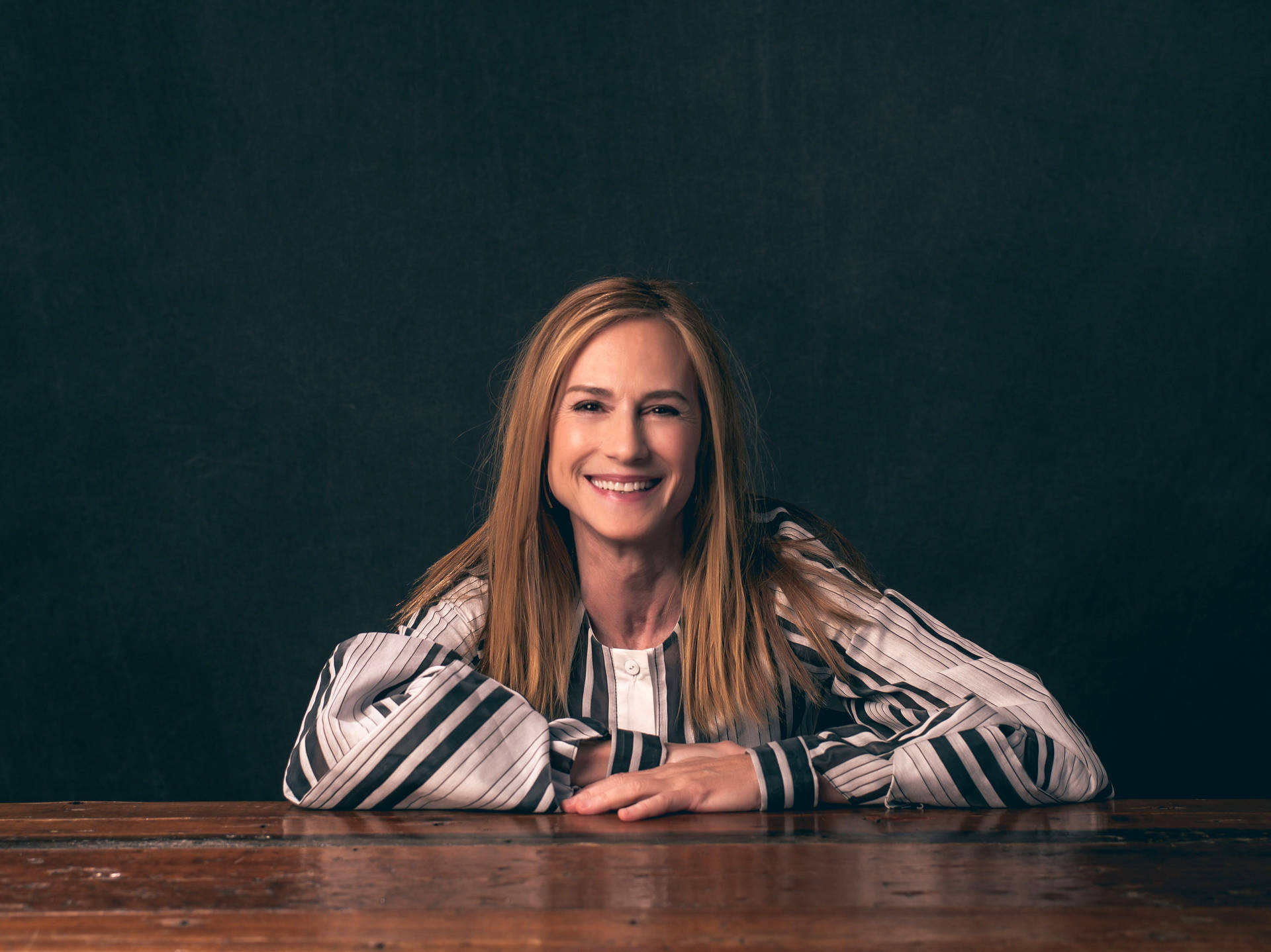 Holly Hunter Sitting Pose Smile Arms Table Background