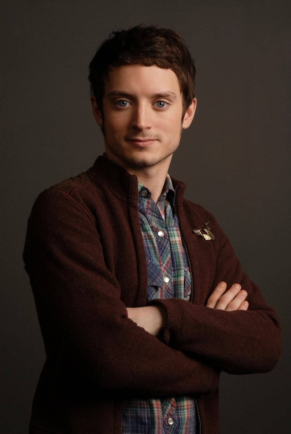 Hollywood Actor Elijah Wood Captured In A Stylish Brown Padded Jacket Background