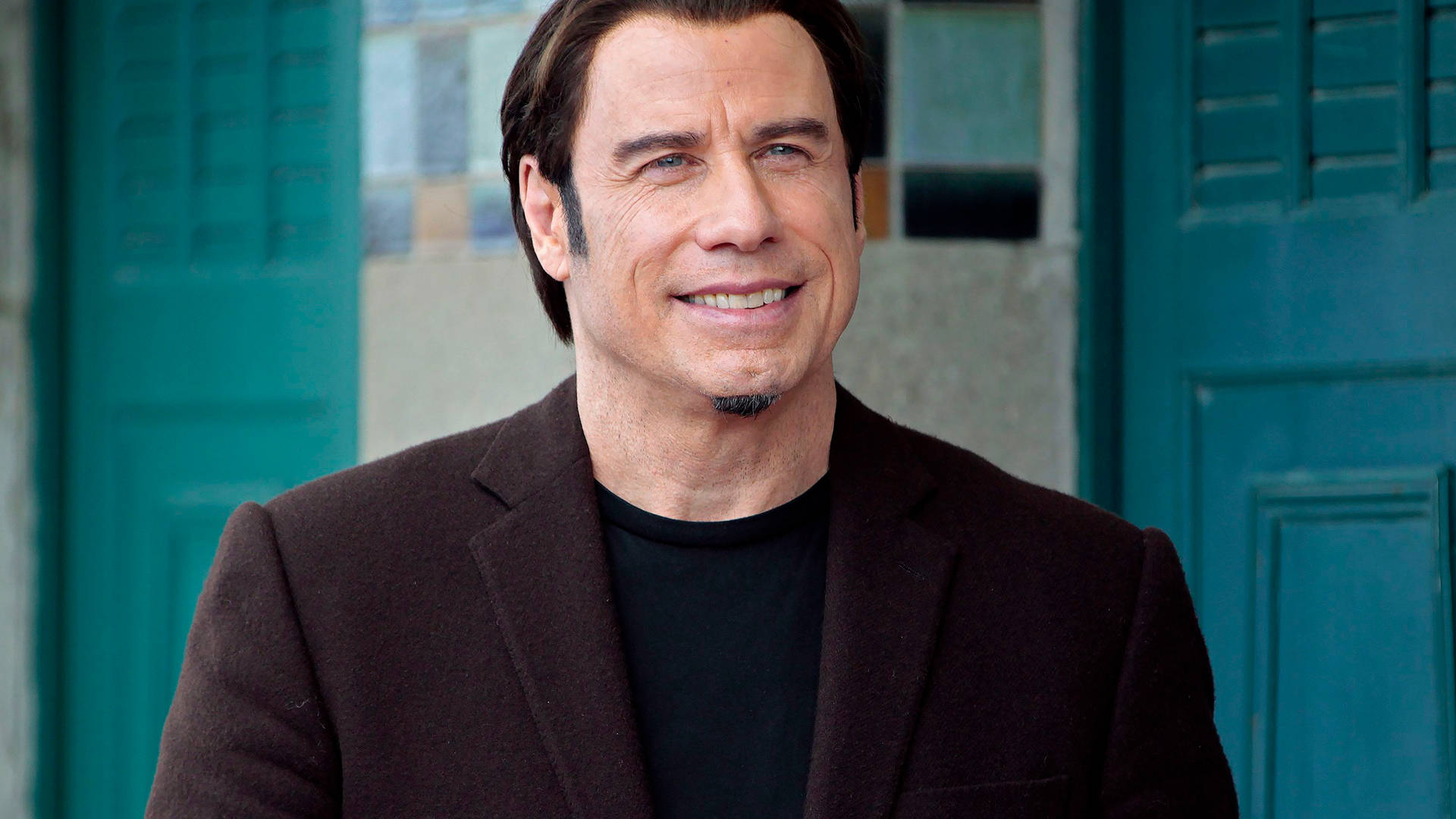 Hollywood Icon John Travolta Looking Handsome In A Black Suit Background