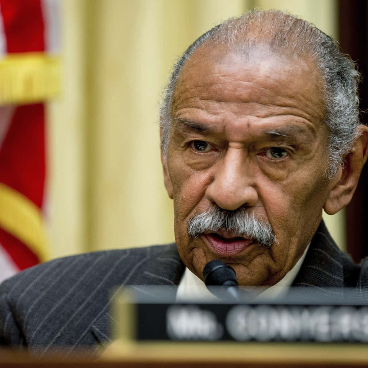 Honorable John Conyers In A Blue Tie And Gray Suit Background