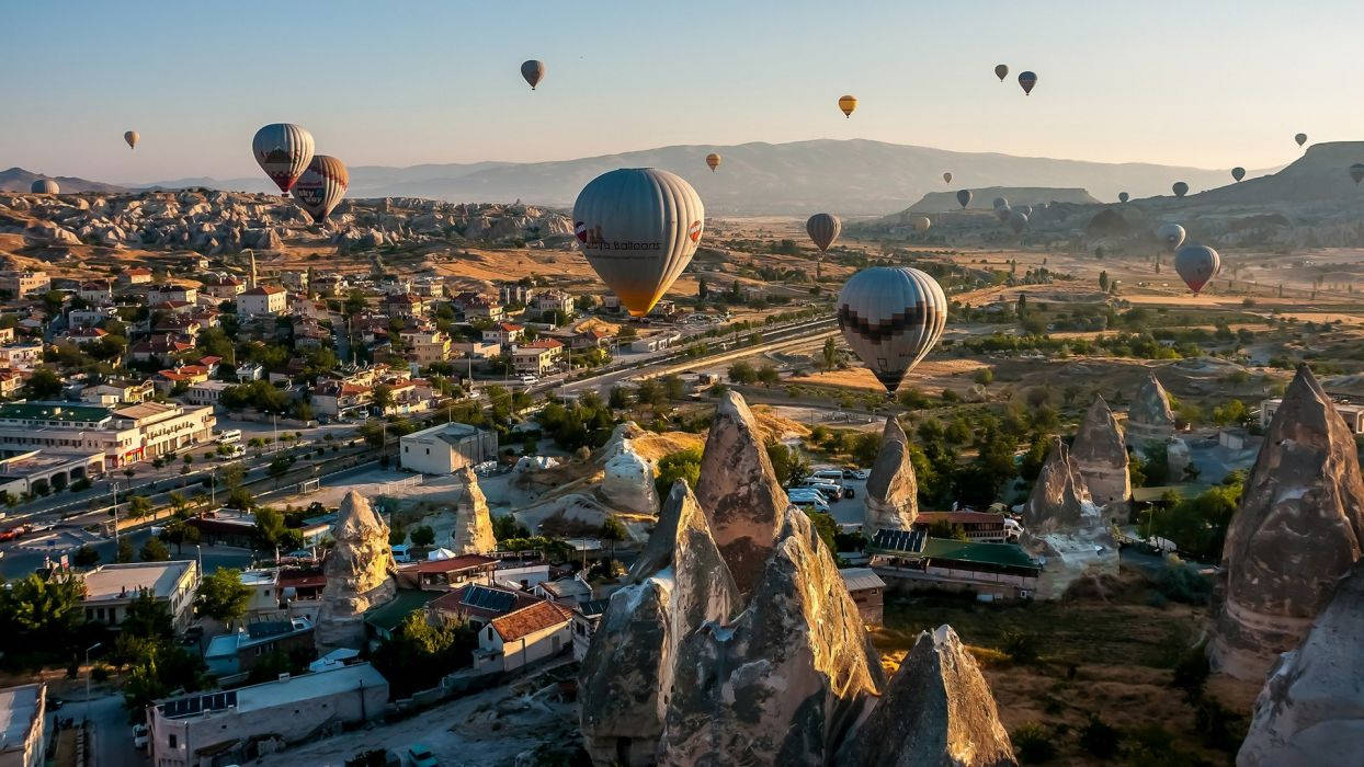 Hot Air Balloons Flying Over A Town Background