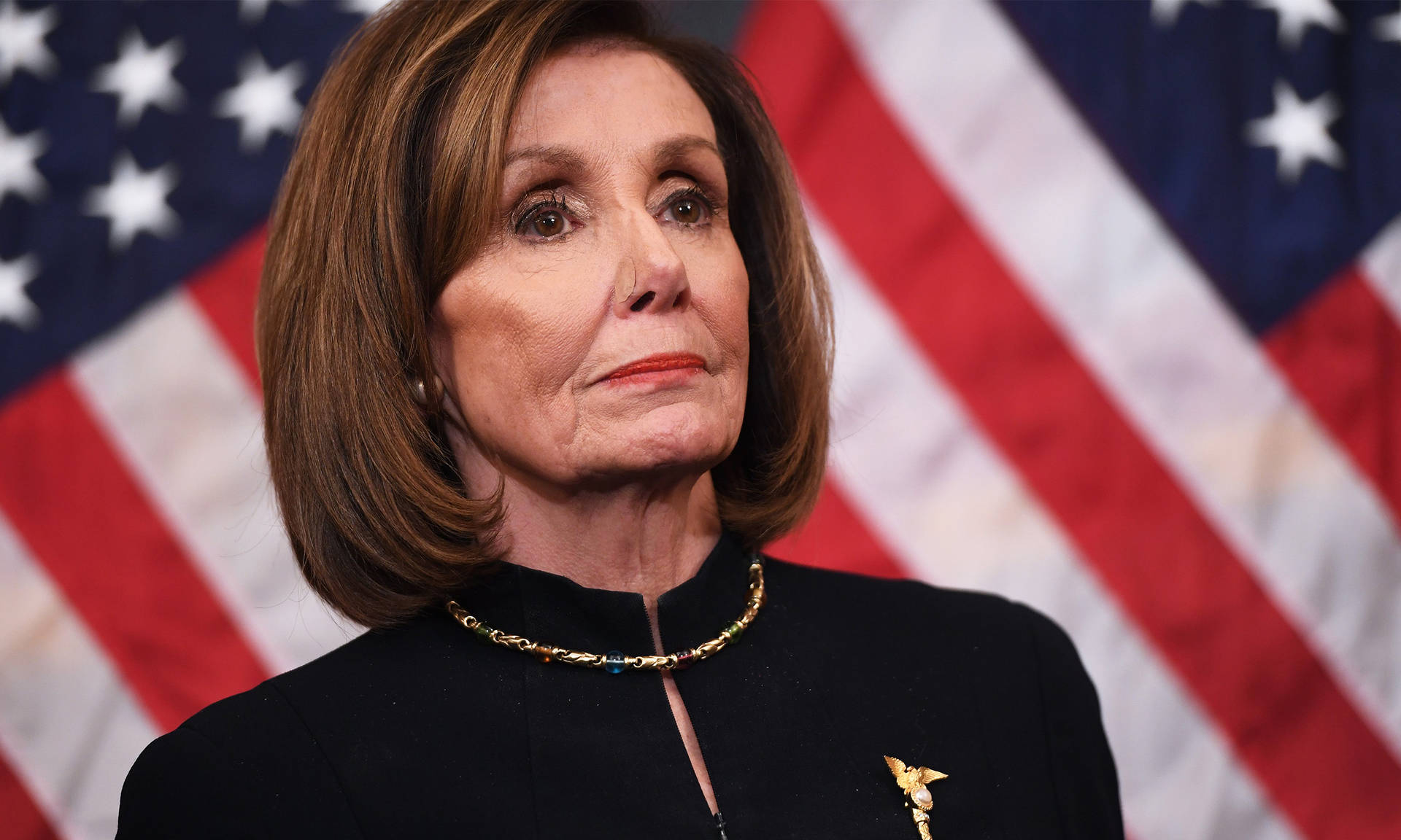 House Speaker Nancy Pelosi In A Formal Black Dress Standing Amidst Us Flags Background