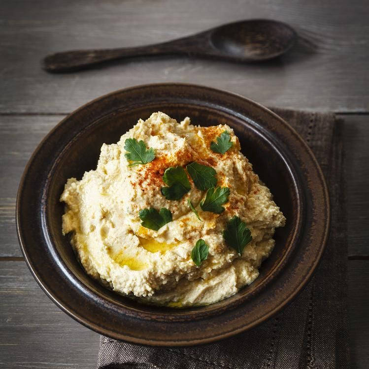 Hummus In Black Bowl With Black Spoon Background