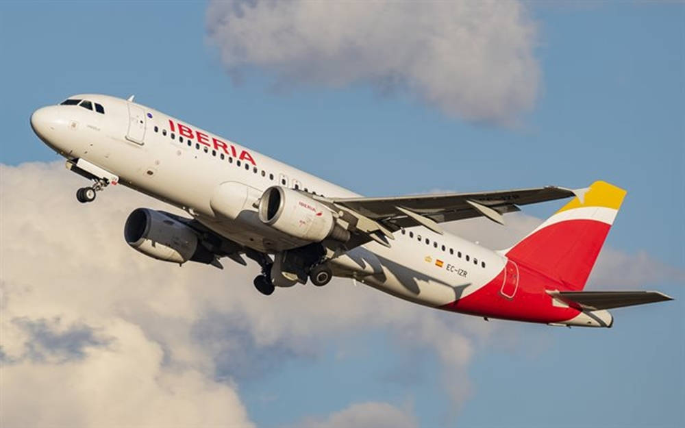 Iberia Airlines Airplane Gliding In Cloudy Skies Background