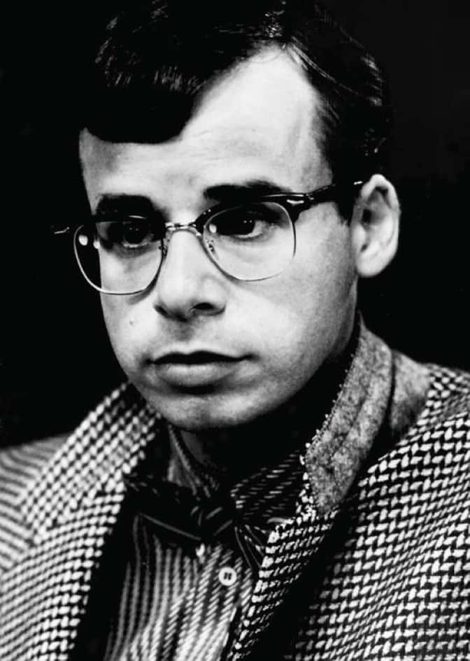 Iconic Actor Rick Moranis Sitting At A Cafe Background