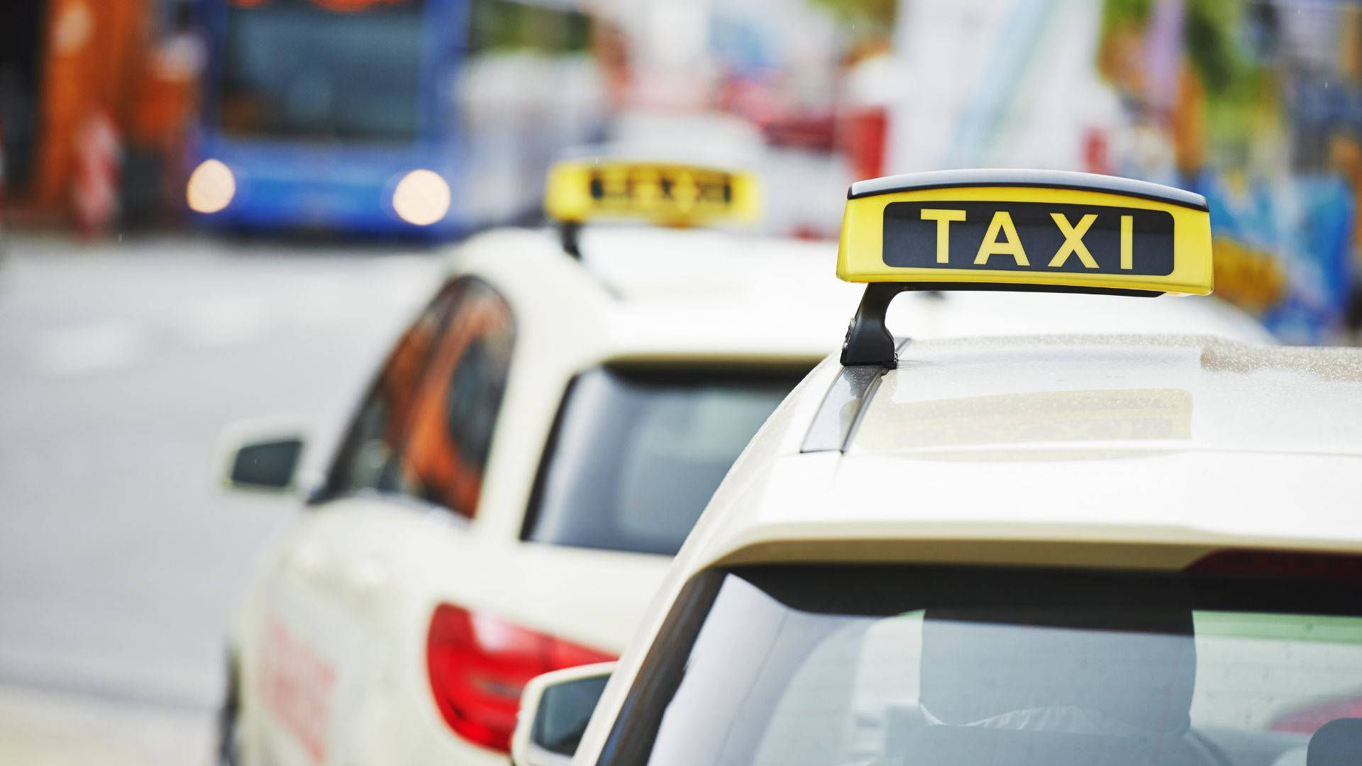 Iconic Black And Yellow Taxi With Rooftop Sign In A Cityscape Background