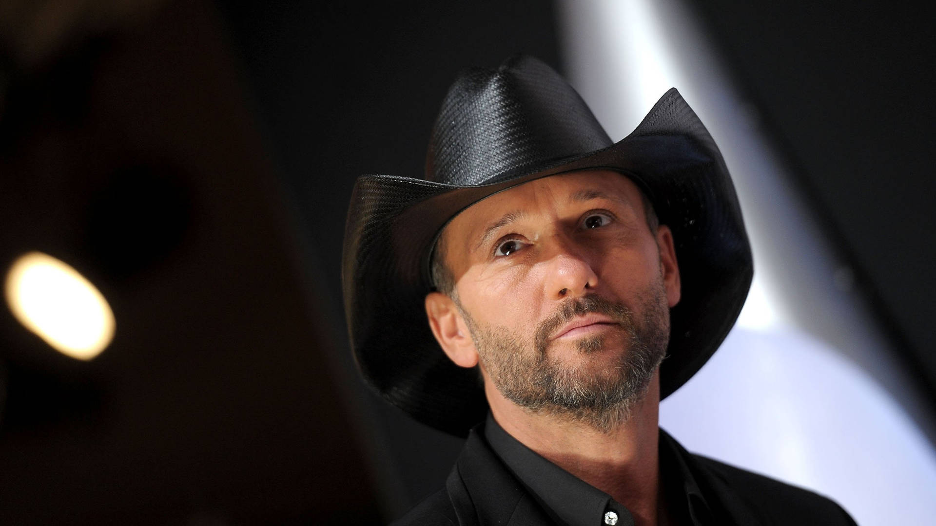 Iconic Country Star Tim Mcgraw Illuminated By Spotlights Background