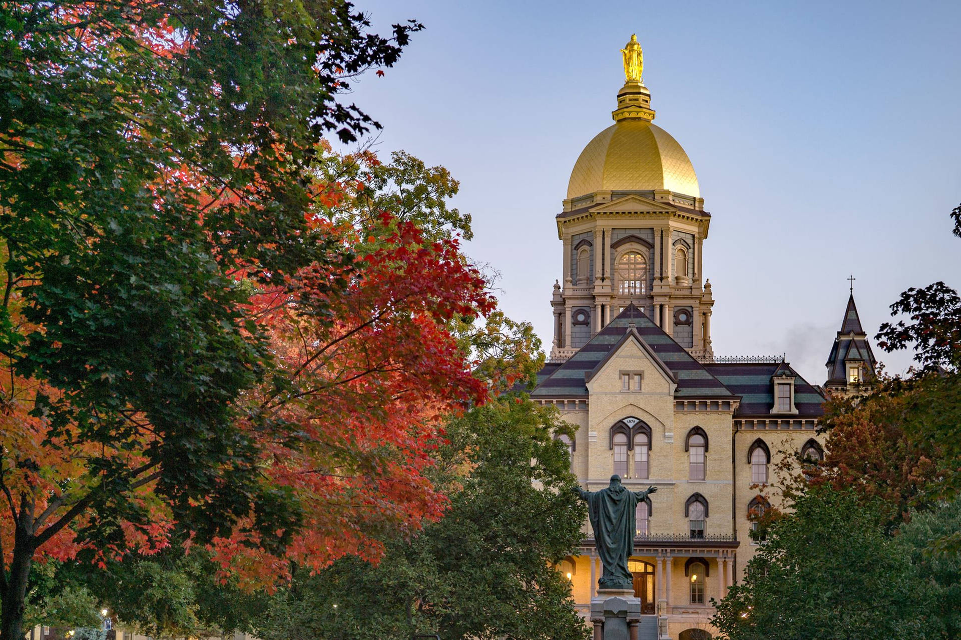 Iconic Golden Dome Of The University Of Notre Dame Against A Serene Backdrop Background