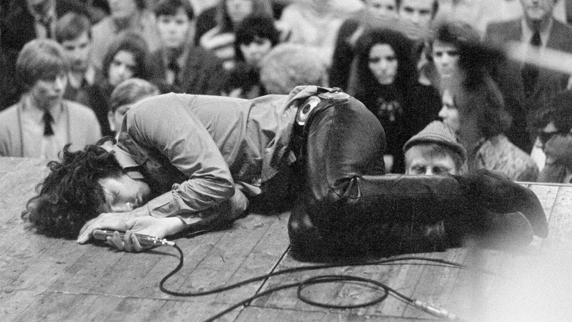 Iconic Image Of Jim Morrison Asleep On Stage Background