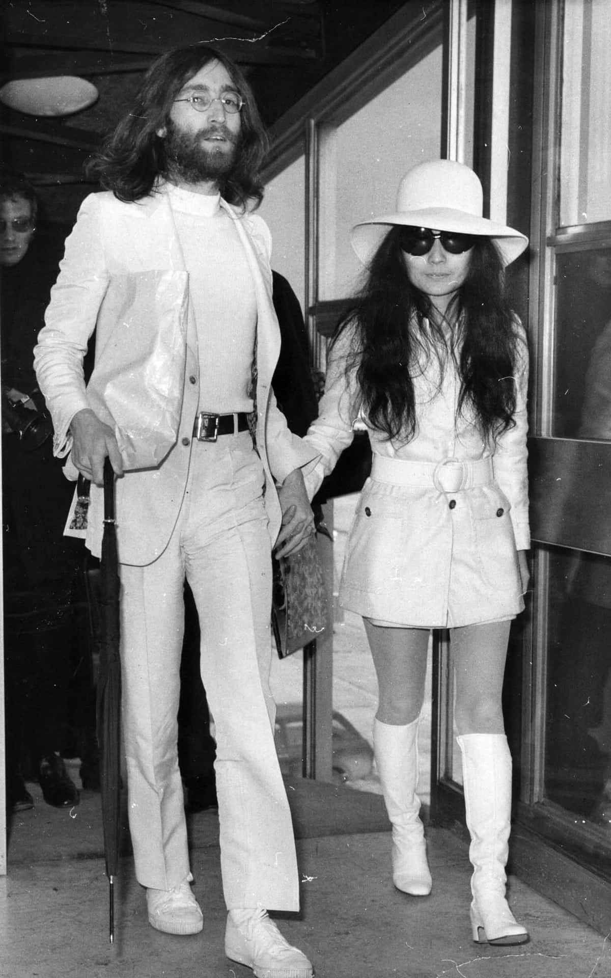 Iconic Photo Of Yoko Ono Walking Hand In Hand With John Lennon Background