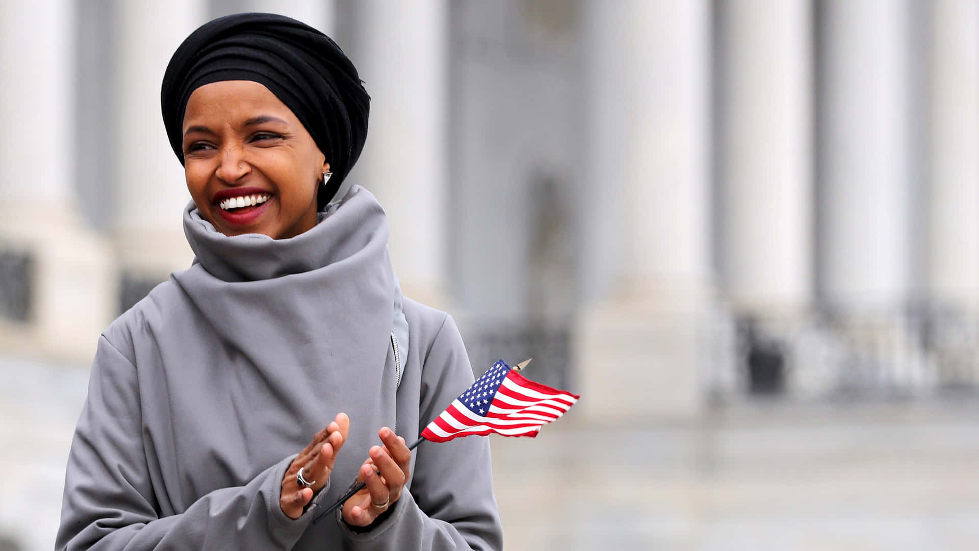 Ilhan Omar Holding A Tiny Flag Background