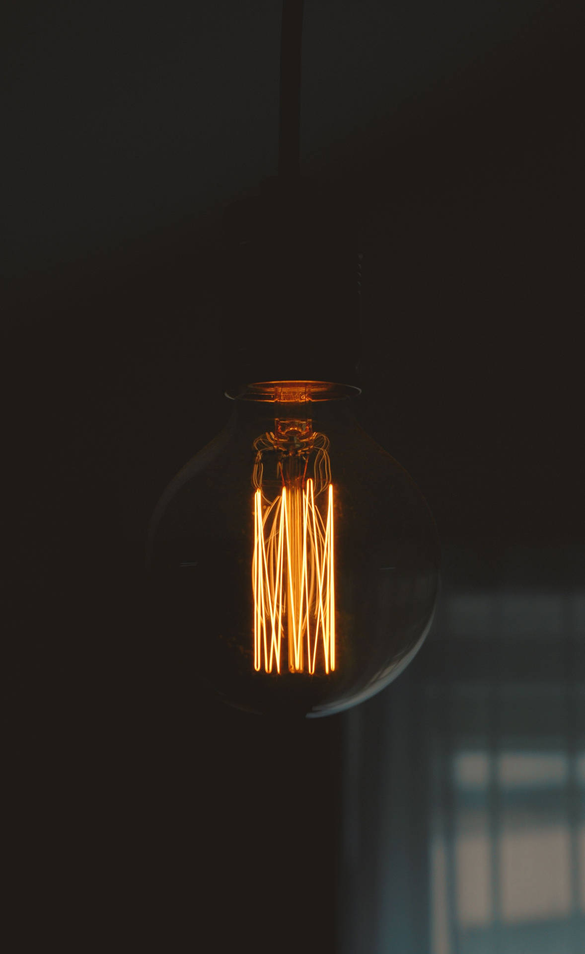 Illuminated Oled Lightbulb Against A Dark Background On An Iphone. Background