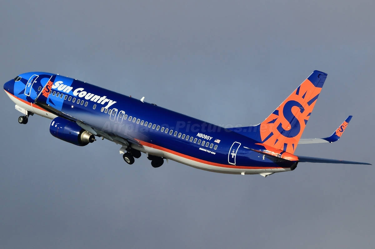 In Flight Aircraft Of Sun Country In Dark Sky Background