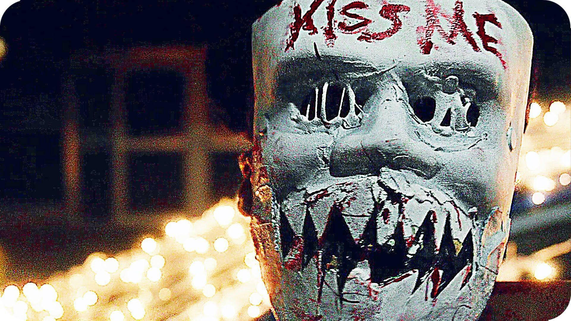 Intense Moment From The Purge Showcasing The Infamous 'kiss Me' Mask Background