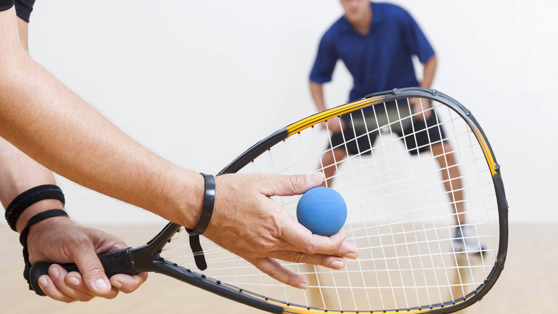 Intense Racquetball Match Between Two Strong Men Background