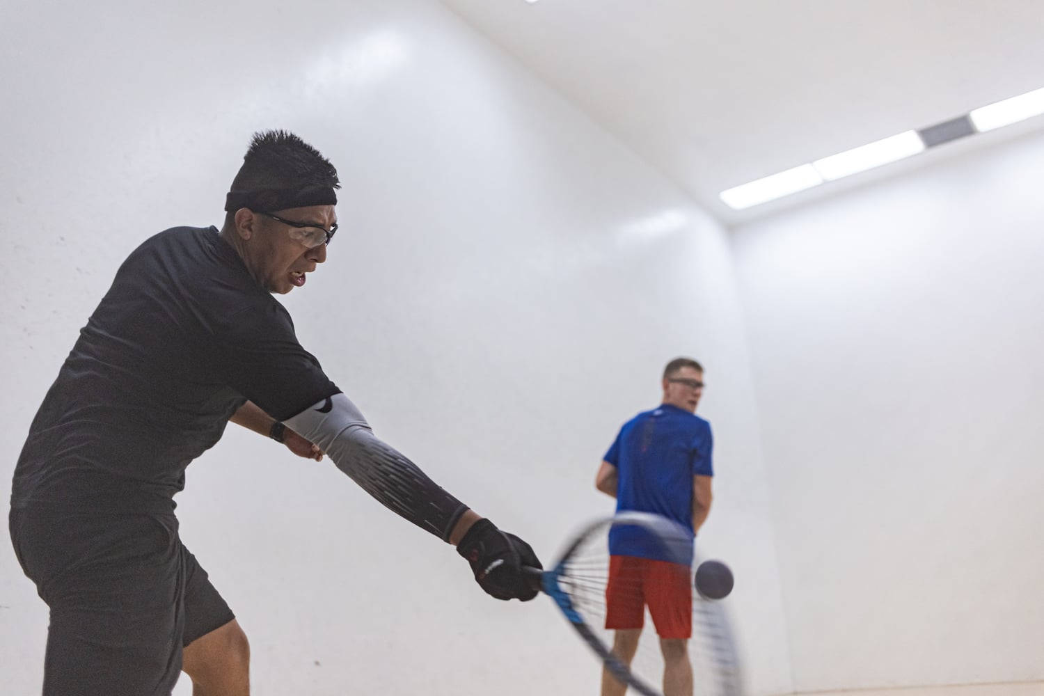 Intense Racquetball Match - Man Forcefully Hitting Ball Background