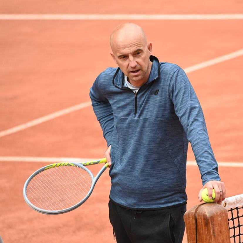 Ivan Ljubicic Intensely Leaning On Tennis Net Background