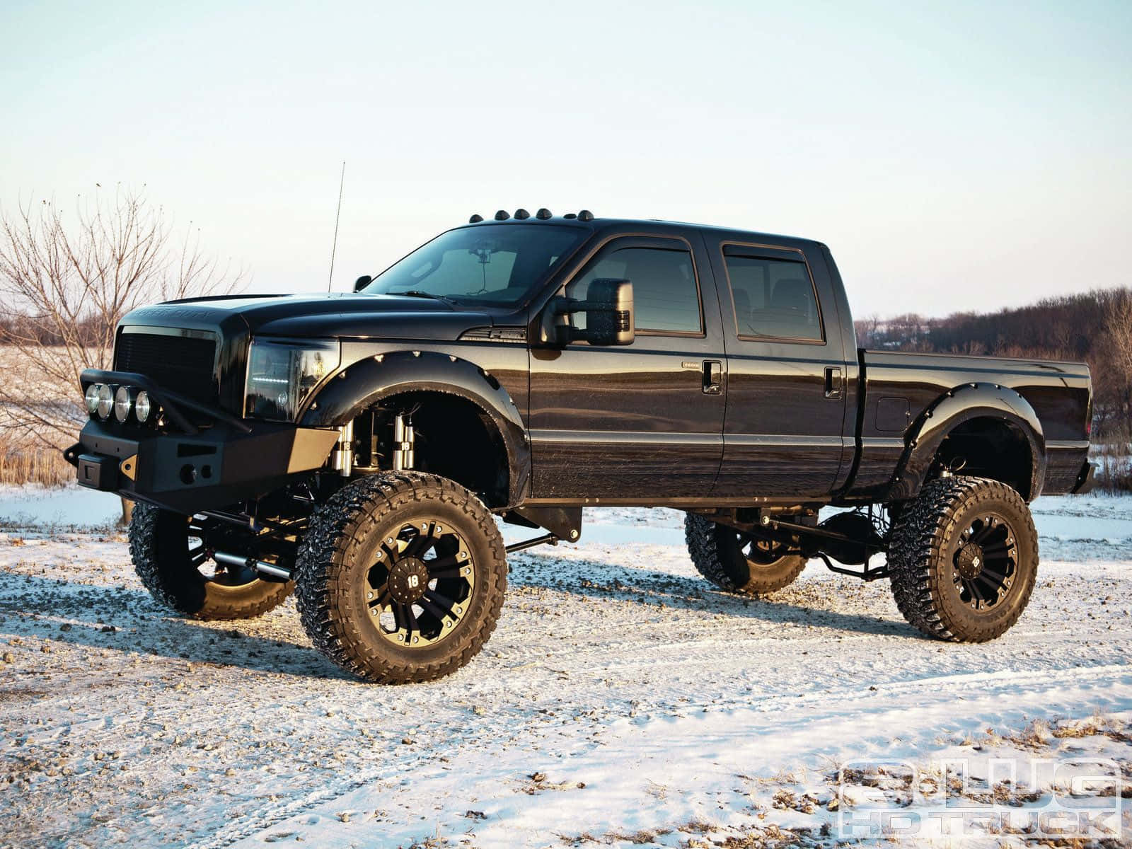 Jacked Up Trucks Driving Through Snowy Road Background